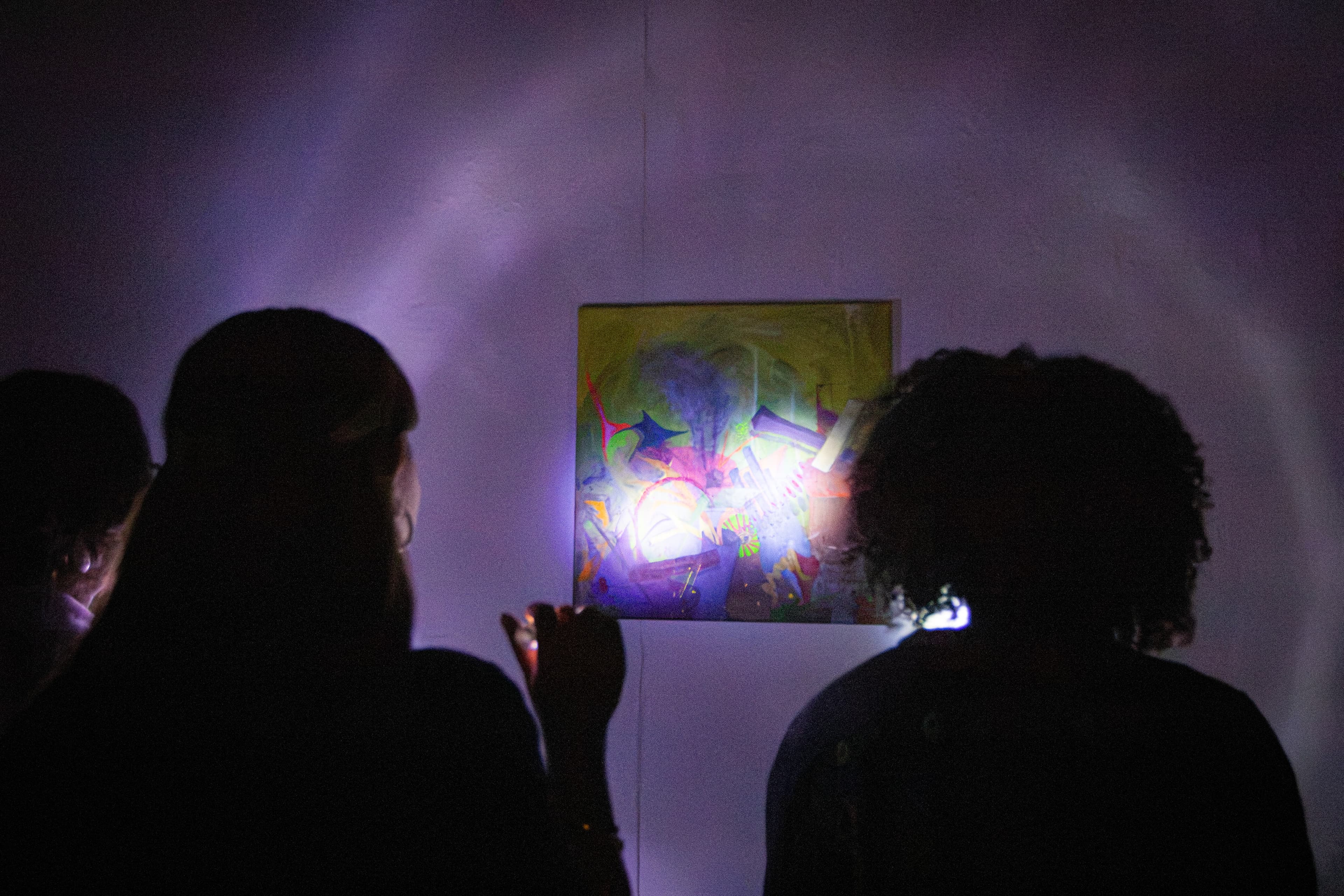 Students use flashlights to view "Scrap Yard," a mixed media piece by Natalie Potter, at the "About Looking" exhibition hosted by The Basement Gallery, on Friday, Oct. 23. (Jenna Lee / Aggie)