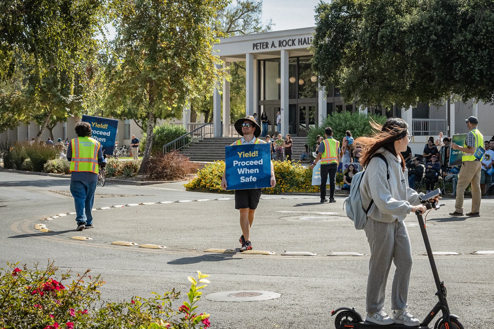 Transportation workers hold signs about bike safety in the middle of the Silo bike circle during the first day of classes on Wednesday, Sept. 23. (Julia Heron-Watts / Aggie)