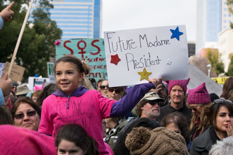 A young marcher shows another child her “Future Madame President” sign. (BRIAN LANDRY / AGGIE)