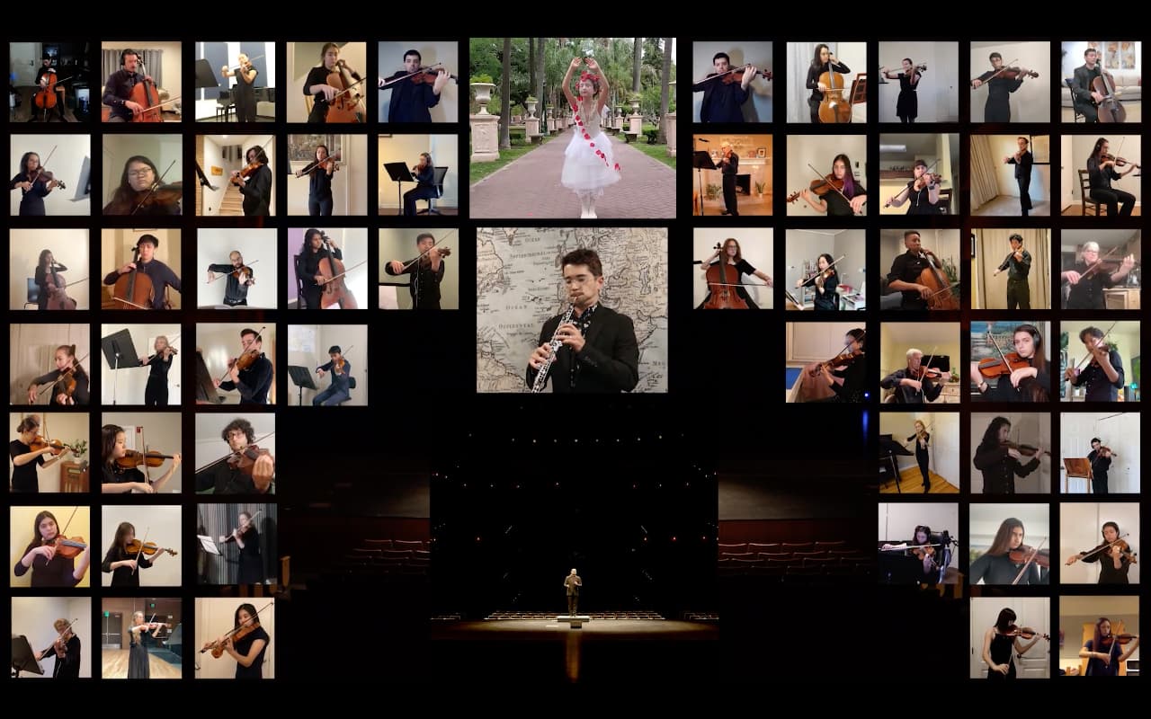 A computer screen filled with people playing instruments through Zoom, conductor sits alone in the center of an empty theater