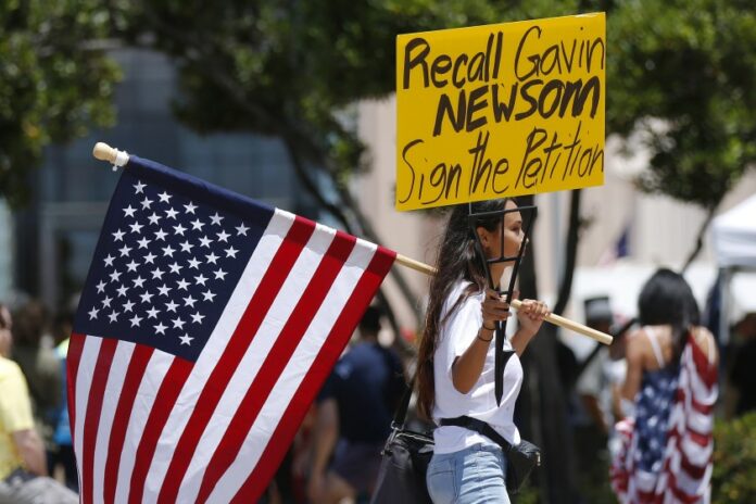Photo of protesters holding signs to recall Gavin Newsom